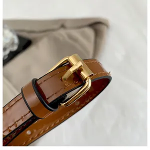 Nahaufnahme des glänzenden braunen Lederhandtaschenriemens mit goldener Metallschnalle, exquisite.