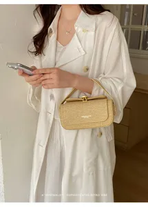 Dettaglio di una elegante borsa a mano in paglia intrecciata con chiusura metallica.