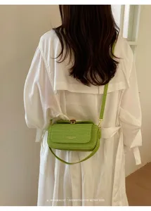 Dettaglio borsa a tracolla intrecciata verde, design retro elegante con chiusura.