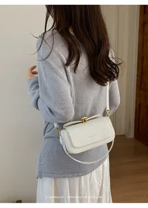Vista dettagliata di una borsa a tracolla retrò bianca minimalista indossata, chiusura dorata.