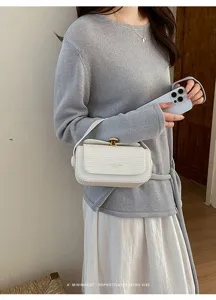 Primo piano di una borsa da donna strutturata e minimalista con chiusura in metallo.