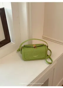 Vista di dettaglio di una borsa a tracolla verde intrecciata con chiusura metallica.