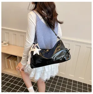 Detailed shot of a black patent leather shoulder bag with chic star charm and casual vibe.