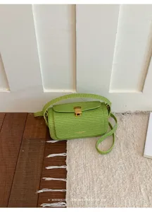 Dettaglio della borsa a mano intrecciata verde con tessuto strutturato e chiusura dorata.