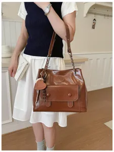 Close-up of retro brown PU leather shoulder bag featuring metallic chain straps and front flap pocket.