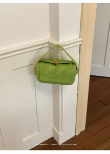Dettaglio borsa a mano intrecciata verde con texture premium e chiusura metallica.