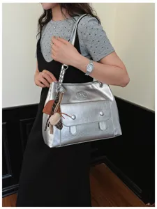 Silver shoulder bag detail showing metallic finish, front pocket, chain strap, and cute charms.
