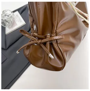 Brown leather tote bag detail view, vintage chic crossbody design with elegant drawstring and metal tips.