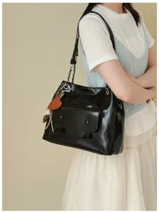 Black retro shoulder bag detail showcasing patent leather texture and metallic chain strap.