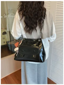 Classic black patent leather shoulder bag with chain strap and stylish front flap pocket.