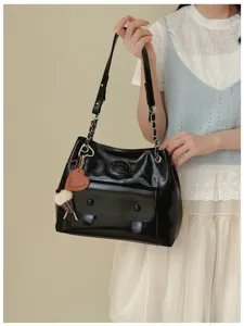 Black glossy leather shoulder bag featuring chain strap, front flap pocket and cute charm.
