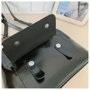 Detailed view of the black patent leather retro satchel bag featuring magnetic snap closure.