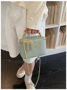 Detailaufnahme der grünen strukturierten Kosmetiktasche mit Goldkette und edler Hardware.