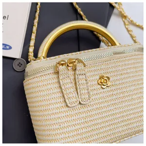 Geflochtene Stroh Kosmetiktasche mit goldenem Griff und Kamelienblüten Emblem Detail.
