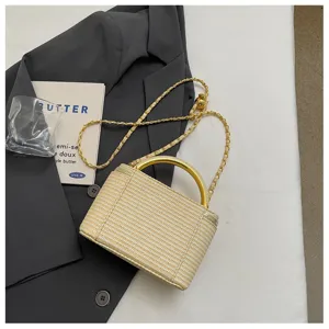 Detailansicht einer Stroh geflochtenen Box-Tasche mit goldenem Metallgriff und Kette.