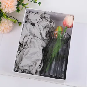 Vista detallada del florero de vidrio y tulipanes artificiales en caja de regalo.