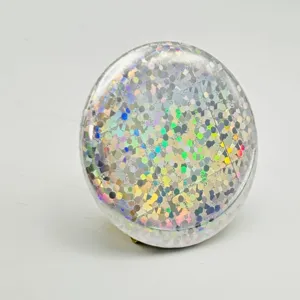 Holographic glitter badge detail shot showcasing sparkling light effects and smooth round surface.
