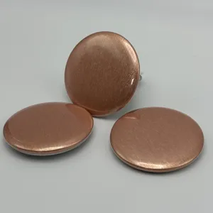 Close-up detail view of rose gold brushed metal round badge pins with textured finish.