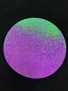 Gros plan sur le papier texturé effet peau de poire holographique pour badges ronds.
