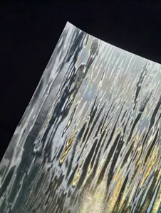 Close-up detail shot of holographic laser backing paper showing shimmering ripple texture.