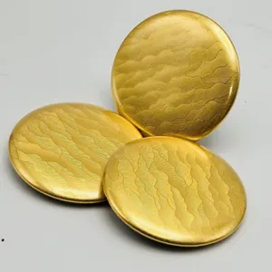 Gold metal badge backing discs with delicate water wave texture for custom anime pin crafts detail.
