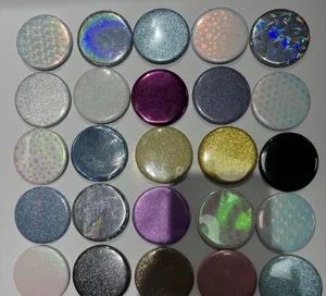 Detailed view of 25 holographic glitter badge covers in various patterns for DIY crafts.
