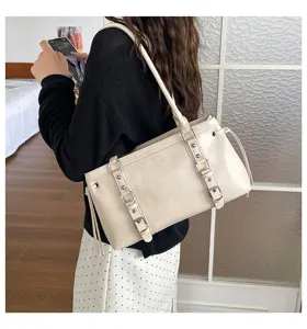 Detail van de beige schoudertas met dubbele gespriemen en grote opbergcapaciteit.