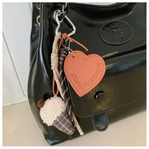 Detailed view of women's black shoulder bag with cute heart tag and plush charm accessory.