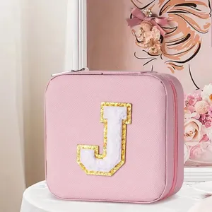 Detail view of pink square jewelry storage box featuring a sparkly letter J patch.