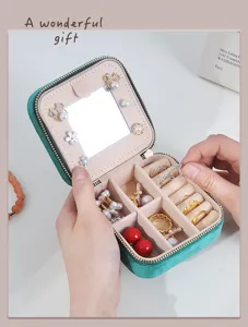 Green velvet portable jewelry box detail showing compact mirror and ring storage slots.