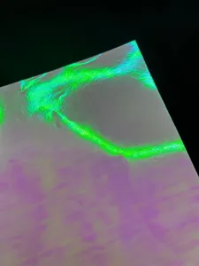 Close up view of holographic glitter specialty paper showcasing reflective green light texture details.
