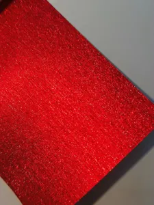 Close-up of red glitter specialty craft paper showing fine sparkling texture detail.