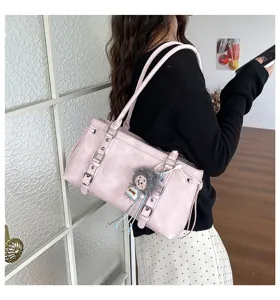 Detailfoto van de roze retro schoudertas met gespriemen en een schattige poppenhanger eraan.
