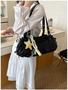 Detail shot of black pleated shoulder bag with star charm and braided ribbon, stylish look.