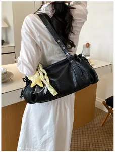 Detailed view of black wrinkled shoulder bag with chic yellow star charm in daily scene.