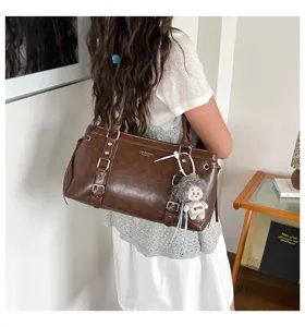 Gedetailleerd overzicht van retro bruine schoudertas met gespen en schattige pluche poppenhanger.