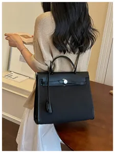 Vue détaillée du sac à main Kelly noir avec serrure métallique et bandoulière élégante.