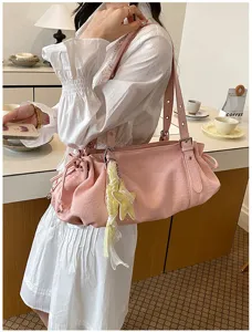 Detail view of the pink pleated shoulder bag with star charm in a cozy room setting.