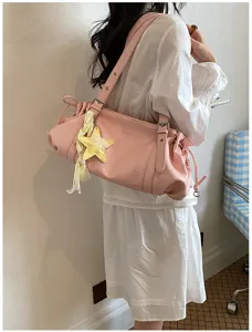 Detail view of the stylish pink pleated shoulder bag featuring a cute yellow star charm accessory.