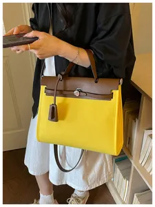 Vue détaillée du sac à main Kelly en toile jaune et cuir marron avec poignée et bandoulière.
