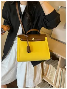 Sac à bandoulière bicolore jaune et marron, vue de détail style Kelly classique.
