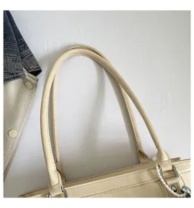Detailopname van de beige lederen schoudertas handgreep, fijne afwerking en strakke stiksels.