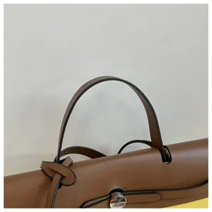 Vue rapprochée détaillée de la poignée de sac à main en cuir marron et du fermoir en métal.