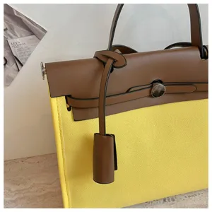 Vue détaillée de la sangle et de la serrure de sac à main Kelly en toile jaune et cuir marron.