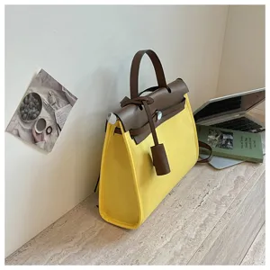 Vue détaillée du sac à main jaune en toile et cuir marron, élégant sac porté épaule chic.
