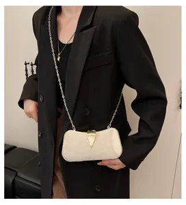 Elegant champagne evening clutch bag with gold chain and leaf clasp detail for parties.