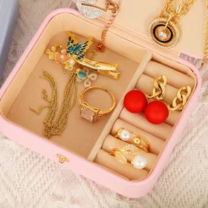 Boîte à bijoux de voyage rose avec plusieurs compartiments et doublure en velours doux.