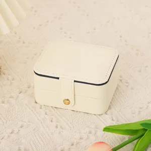 Vue détaillée de la boîte à bijoux portable en cuir blanc crème, design compact chic.