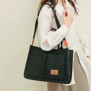 Canvas shoulder crossbody tote bag with front pocket and contrast leather tag detail for women.