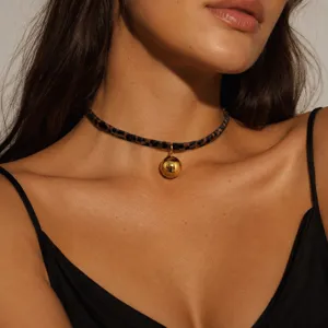 Detalle de un elegante collar gargantilla con estampado de leopardo y colgante esférico.